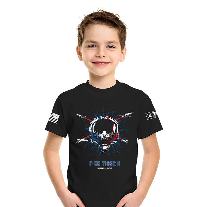A young boy wearing a black short-sleeve t-shirt with a patriotic 'F-22 Tiger II' graphic on the front, featuring a skull and jet design in red, white, and blue, with a US flag on the right sleeve and a star on the left sleeve, set against a plain white background.